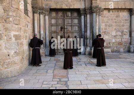 Franziskaner-Brüder beten vor der verschlossenen Tür der Grabeskirche inmitten der Coronavirus COVID-19 Pandemie-Krise in der Altstadt von Jerusalem Israel Stockfoto