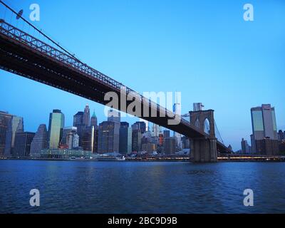 Unter der Brooklyn Bridge, mit einem World Trade Center und Lower Manhattan im Morgengrauen, vom East River, Manhattan, New York, USA aus gesehen Stockfoto