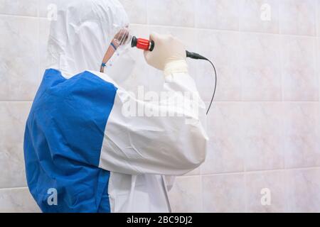 Arzt im Schutzanzug mit kurzem Fiberendoskop während der Pandemie in einem armen Land. Konzept der epidemischen Krankheit. Filmkörnung. Stockfoto