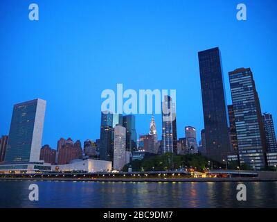 Gebäude des Hauptquartiers der Vereinten Nationen mit Chrysler Building im Hintergrund im Morgengrauen, vom East River, New York, USA aus gesehen Stockfoto