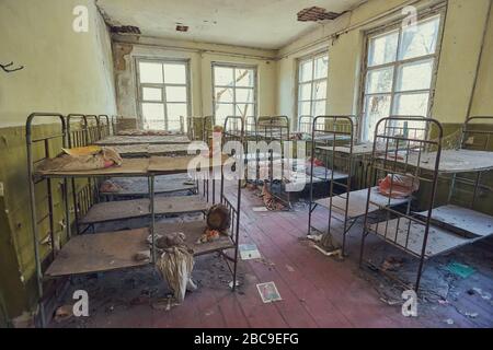 Pripyat, Ukraine - 25. April 2019: Zimmer voller leerer Metallbettrahmen im aufgelassenen Kindergarten Stockfoto