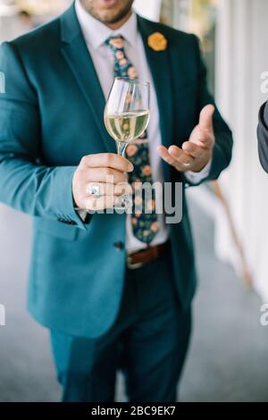 Weißwein in der Hand des Menschen im blauem Anzug Stockfoto