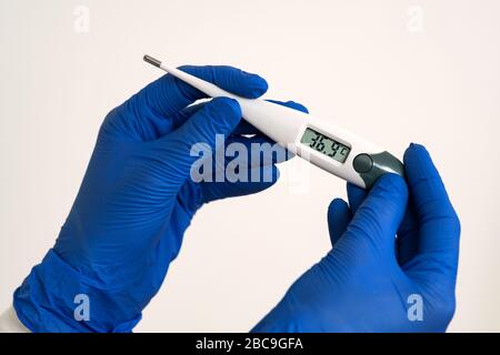 Die Hände in blauen Schutzhandschuhen mit einem leicht hohen Temperaturbereich halten. Stockfoto