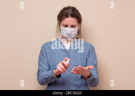 Junge Frau sprüht ihre Hände mit Desinfektionsmittel, die sich vor Viren schützt. Studio gedreht Stockfoto