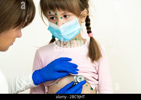 Arzt untersucht Mädchen mit grünen Ausschlägen auf Gesicht und Bauch erkrankt an Windpocken, Masern oder Röteln Virus. Stockfoto