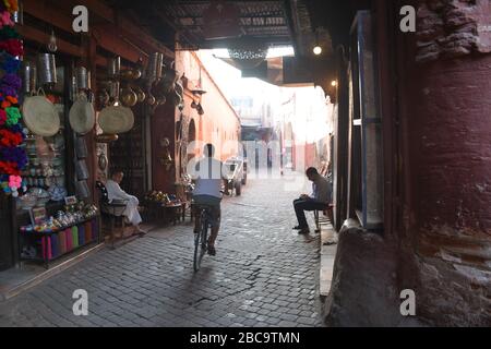 Ein Einheimischer fährt an einem ruhigen frühen Abend in Marrakesch Medina, Marokko, eine schmale Gasse entlang. Stockfoto