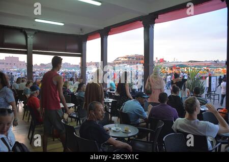 Touristen und Einheimische sehen den Sonnenuntergang von der Terrasse im Erdgeschoss des Le Grand Balcon Du Cafe Glacier auf Djemma El Fna, Medina von Marrakesch, Marokko. Stockfoto