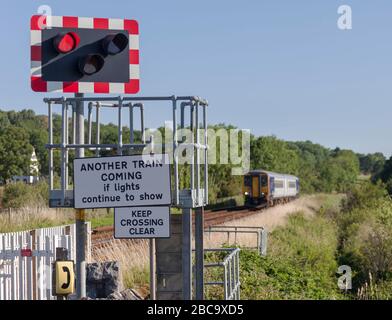 Der Zug nähert sich der automatischen Halbschrankendurchfahrt in Silverdale, die die roten Blinkleuchten zeigt Stockfoto