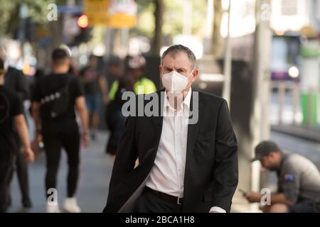 Ein Mann geht die Elizabeth Street im zentralen Geschäftsviertel von Melbourne entlang und trägt eine N95-Maske, Melbourne Australien. Stockfoto