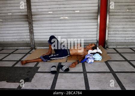 Antipolo City, Philippinen - 2. April 2020: Obdachloser philippinischer Mann schläft auf dem Seitenweg vor einem geschlossenen Laden während der Sperrung oder Gemeinde qu Stockfoto