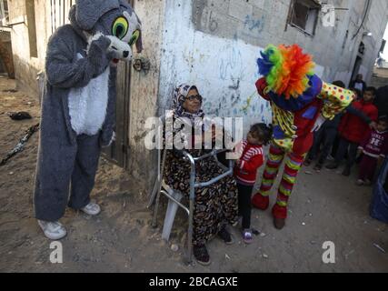 Gaza, Palästina. April 2020. Palästinensische Jugendliche, die als Clowns verkleidet sind und Schutzhandschuhe tragen, sind eine Straßenvorstellung, um Kinder zu unterhalten, die aufgrund des Corona-Virus-Ausbruchs in Khan Yunis, dem südlichen Gazastreifen, zu Hause gefangen sind. Credit: SOPA Images Limited/Alamy Live News Stockfoto