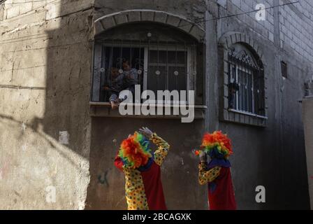 Gaza, Palästina. April 2020. Palästinensische Jugendliche, die als Clowns verkleidet sind und Schutzhandschuhe tragen, sind eine Straßenvorstellung, um Kinder zu unterhalten, die aufgrund des Corona-Virus-Ausbruchs in Khan Yunis, dem südlichen Gazastreifen, zu Hause gefangen sind. Credit: SOPA Images Limited/Alamy Live News Stockfoto