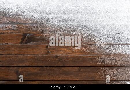 Schnee auf einem Holzboden einer offenen Terrasse im Hintergrund. Stockfoto