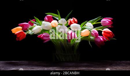 Tulpen in einer Glasvase vor Holz Stockfoto