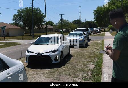 Groveland, Vereinigte Staaten. April 2020. April 2020 - Groveland, Florida, Vereinigte Staaten - VERZEICHNET EIN Freiwilliger die Anzahl der Familien, die ankommen, um Lebensmittel von der Second Harvest Food Bank of Central Florida bei einem Drive-Through-Event für bedürftige Familien am 3. April abzuholen, 2020 im Faith Neighborhood Center in Groveland, Florida, in der Nähe von Orlando. Die Coronavirus Pandemie hat Tausende von lokalen Servicemitarbeitern und Angestellten des Freizeitparks außer Arbeit gesetzt und belastet die Lebensmittelbanken in der Region. Credit: Paul Hennessy/Alamy Live News Stockfoto