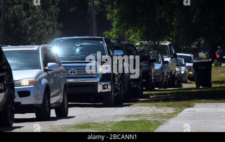 Groveland, Vereinigte Staaten. April 2020. 3. April 2020 - Groveland, Florida, Vereinigte Staaten - EINE Reihe von Autos wird wieder aufgebaut, während die Fahrer warten, um Lebensmittel von der Second Harvest Food Bank of Central Florida bei einer Drive-Through-Veranstaltung für bedürftige Familien am 3. April abzuholen. 2020 im Faith Neighborhood Center in Groveland, Florida, in der Nähe von Orlando. Die Coronavirus Pandemie hat Tausende von lokalen Servicemitarbeitern und Angestellten des Freizeitparks außer Arbeit gesetzt und belastet die Lebensmittelbanken in der Region. Credit: Paul Hennessy/Alamy Live News Stockfoto