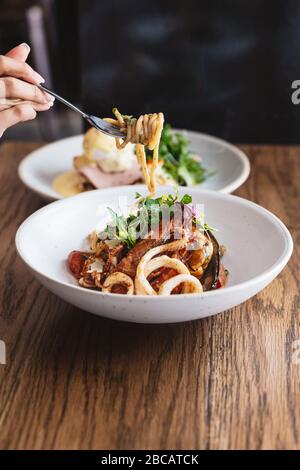 Hand kneifen Spaghetti Meeresfrüchte und mit einer Gabel gehoben: Spaghetti mit Garnelen, Tintenfische, Muscheln in Olivenöl, Chili und Knoblauch gekocht. Stockfoto