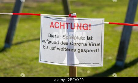 Nahaufnahme des Hinweisschildes am abgesperrten Spielplatz (Spielplatz). Mit einem typisch deutschen Wort: Achtung! (Achtung!). Einschränkungen aufgrund von Covid-19/Coronavirus. Stockfoto