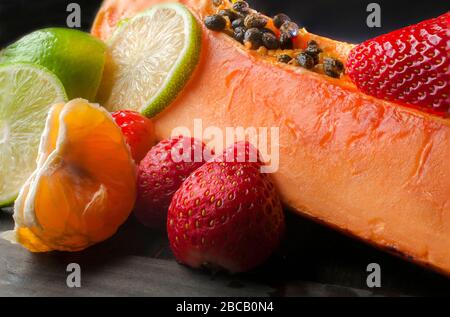 Stilllebenfotografie, Obst auf einem Holztisch mit Papaya-Erdbeeren-Zitronenscheiben Stockfoto