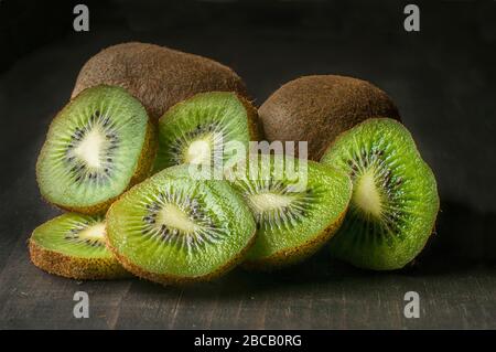 Standbildaufnahmen, dunkle Lebensmittel oder Low-Key-Licht, Kiwis auf einem Holztisch, Nahaufnahme oder Makro. Stockfoto