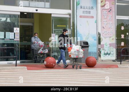 Dallas, USA. April 2020. Zwei Kunden, die Masken tragen, gehen am 3. April 2020 aus einem chinesischen Supermarkt in Plano, einer Vorstadt von Dallas, Texas, in den Vereinigten Staaten. US-Präsident Donald Trump sagte am Freitag, dass die Centers for Disease Control and Prevention (CDC) nun empfiehlt, dass Amerikaner Stoff-Gesichtsbeläge tragen, um sich gegen COVID-19 zu schützen. "Die CDC berät den Einsatz von nicht-medizinischen Stoffbedeckungen als freiwillige Gesundheitsmaßnahme", sagte Trump einer Unterweisung des Weißen Hauses. "Es ist freiwillig. Sie schlugen für einen bestimmten Zeitraum vor." Credit: Dan Tian/Xinhua/Alamy Live News Stockfoto