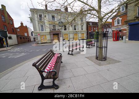 Öffentliche Räume Sitzbänke wurden in Wimborne Minster Dorset aufgrund des Corona-Virus 3. April 2020 aufgemacht. Das Kings Head Hotel am Wimborne Square ist bis auf weiteres geentert. Wie bei der Nichtnutzung von Sitzbänken im öffentlichen Bereich wurde die Botschaft "Stay at Home" aufgrund der Covid 19-Pandemie mit sozialer Distanzierung aufgenommen. Stockfoto