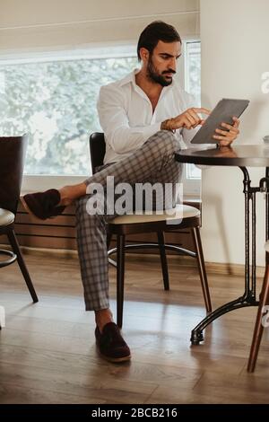 Ernst eleganten bärtigen Mann berühren Tablet-Bildschirm während sitzen in einem Café Stockfoto
