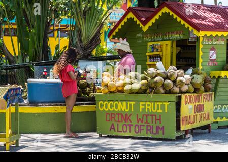 Ocho Rios, Jamaika - 22. April 2019: Eiskalte Kokosnuss-Fruchtsgetränke mit Rum-Stall/Eck-Shop in Rasta-Farben am Kreuzfahrthafen Ocho Rios in der Stockfoto