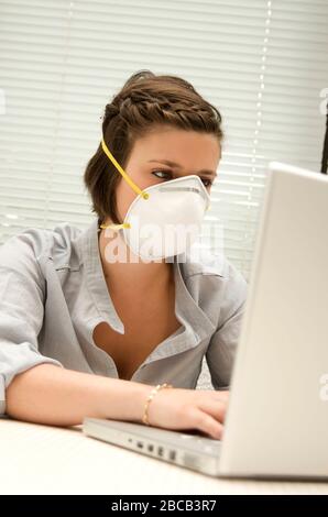 Nahaufnahme einer Coronavirus-Maske, die von einer jungen Frau getragen wird, die im Büro arbeitet Stockfoto