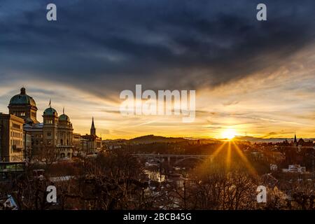 Ein zauberhafter Sonnenaufgang unter dunklem Himmel beleuchtet das Bundeshaus in Bern. Stockfoto