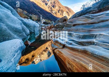 Der Kirchturm von Lavertezzo und die glatten Felsen des Valle Verzasca spiegeln sich im Wasser des Verzasca-Baches wider. Stockfoto