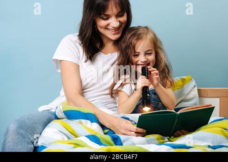 Die junge Mutter liest ihrer Tochter ein Buch, bevor sie ins Bett geht Stockfoto