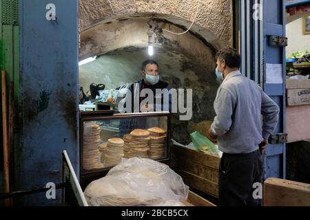 Palästinensischer Verkäufer und Kunde trägt Schutzmaske wegen der COVID-19 Coronavirus-Pandemie, die Pitta-Brot im muslimischen Viertel in der Altstadt von Jerusalem Israel verkauft Stockfoto