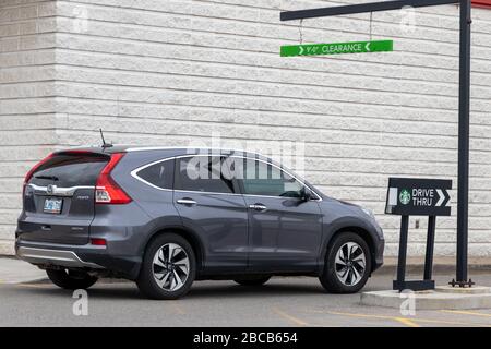 Das Auto betritt den Drive-Thru-Pfad zum Starbucks Coffee Shop, Schild neben dem Auto. Stockfoto