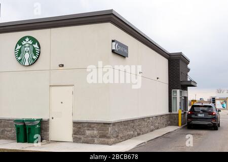 Starbucks Coffee Schild auf der Rückseite eines Ladens, das mit einem Auto am Drive-Thru-Fenster zu sehen ist. Stockfoto