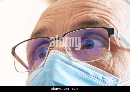 Ein Mann in einer Brille und eine Maske schaut auf den Bildschirm. Nahaufnahme. Porträt eines älteren Spezialisten mit Maske Stockfoto
