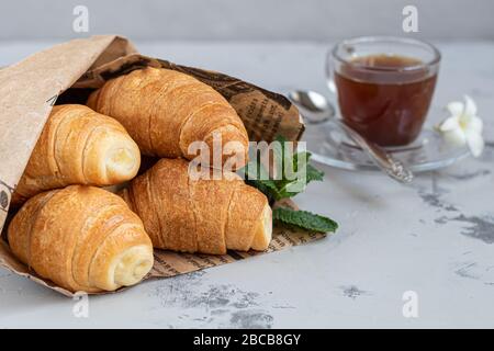 Croissants und Kaffee zum Frühstück mit frischen Himbeerblecken auf hellem Hintergrund. Mit Minze dekoriert. Kopierbereich. Stockfoto