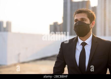 Junge persische Unternehmer denken, während sie Maske tragen, um vor dem Ausbruch des Corona-Virus und der Verschmutzung zu schützen Stockfoto