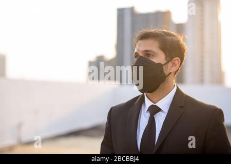 Junge persische Unternehmer denken, während sie Maske tragen, um vor dem Ausbruch des Corona-Virus und der Verschmutzung zu schützen Stockfoto