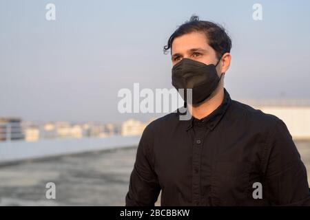 Junge persische Unternehmer denken, während sie Maske tragen, um vor dem Ausbruch des Corona-Virus und der Verschmutzung zu schützen Stockfoto