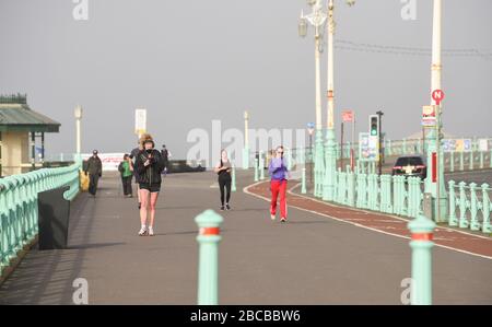 Brighton UK 4. April 2020 - die Sonne beginnt, den Nebel am frühen Morgen zu durchbrechen, während Läufer an der Brighton Seafront an Tag zwölf der Regierungsblockierung während der Coronavirus COVID-19-Pandemie-Krise trainieren. An der Pressekonferenz von gestern Downing Street Coronavirus sagte der Gesundheitsminister Matt Hancock der Öffentlichkeit, dieses Wochenende zu Hause zu bleiben, trotz der Vorhersage von warmem, sonnigem Wetter. Kredit: Simon Dack / Alamy Live News Stockfoto
