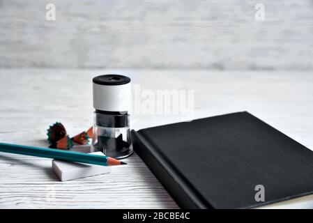 Schwarzer Notizblock, Bleistiftspitzer, Bleistift, elastisch auf hellem Hintergrund Stockfoto