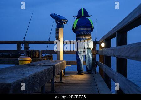 Nachtfischer auf einem Steg an der Ostseeküste bei Schönberg in Holstein Stockfoto