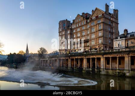 Das Empire Hotel in der Nähe der Pulteney Bridge bei Sonnenaufgang mit der Colonnade unter der Newmarket Row und dem Pulteney Wehr am Fluss Avon, Bath, England Stockfoto