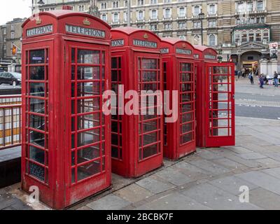 Vier rote traditionelle und traditionelle Telefonzellen stehen in einer Reihe am Strand, London, England, Großbritannien gegenüber der Charing Cross Station. Stockfoto