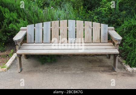 Holzbank im Sommergarten in der Nähe des Gehwegs Stockfoto