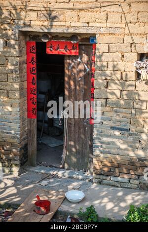 Yangshuo, China - August 2019: Öffnet Türen zum chinesischen Haus mit Holztüren aus Retro-Holz, Ziegelwand und Vintage-Dekoration chinesischer Schriftzeichen Stockfoto