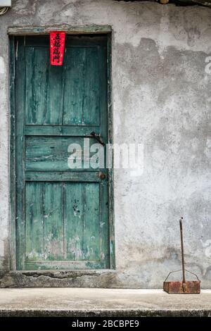Yangshuo, China - August 2019: Geschlossene grüne Holztüren zum chinesischen Haus mit Vintage-Dekoration aus chinesischen Schriftzeichen, die auf einem r geschrieben werden Stockfoto