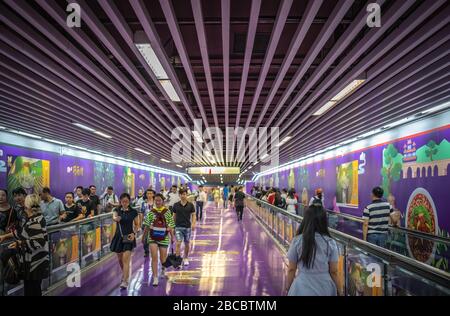 Chongqing, China - August 2019: Pendler, die im farbenfrohen, bemalten U-Bahn-Tunnel zu Fuß unterwegs sind, führen zu U-Bahn-Zügen Stockfoto