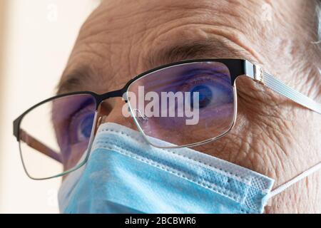 Neuigkeiten anzeigen. Ein Mann in einer Brille und eine Maske schaut auf den Bildschirm. Nahaufnahme. Stockfoto